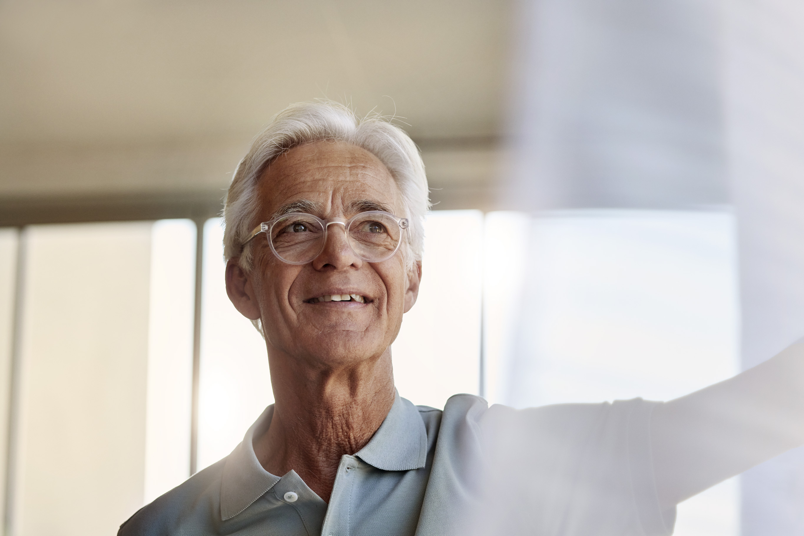 Older white male patient with white hair and glasses having a hopeful expression